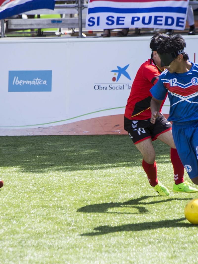 a male blind footballer runs with the ball