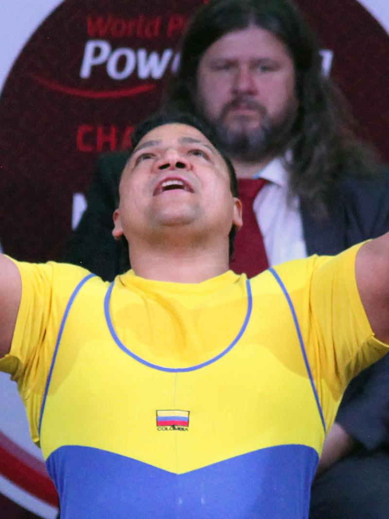 a male powerlifter raises his arms in celebration on the bench