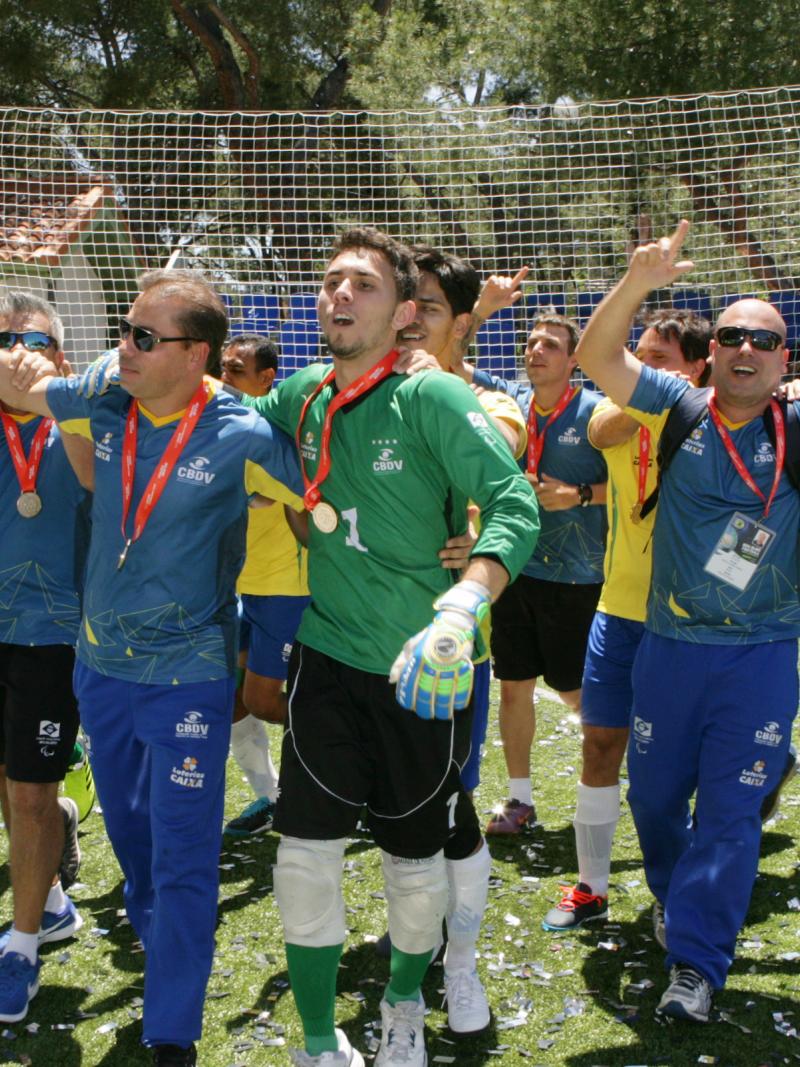 a group of male blind footballers celebrating on the football pitch