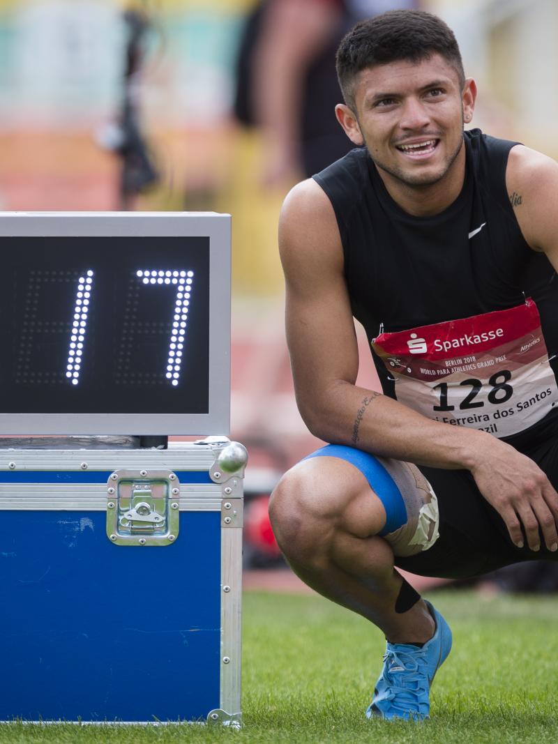 a male Para sprinter stands next to a race clock
