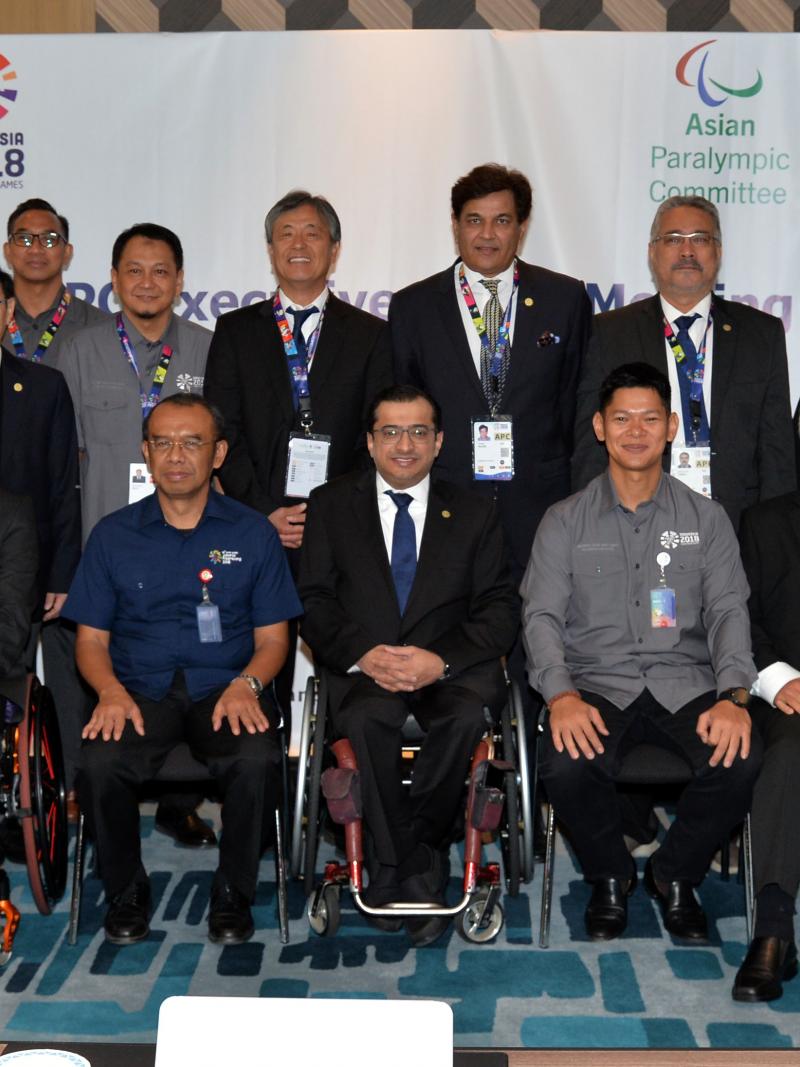 a group of men and women in a boardroom smiling at the camera