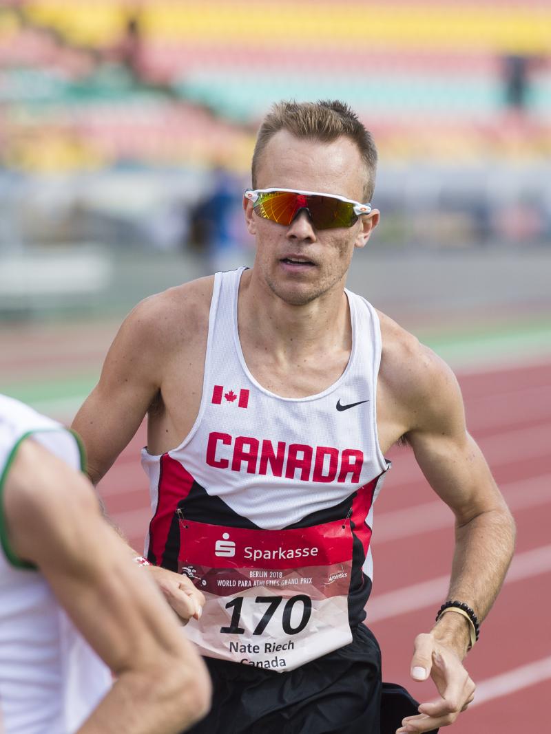 a male Para athlete overtakes another runner on the track