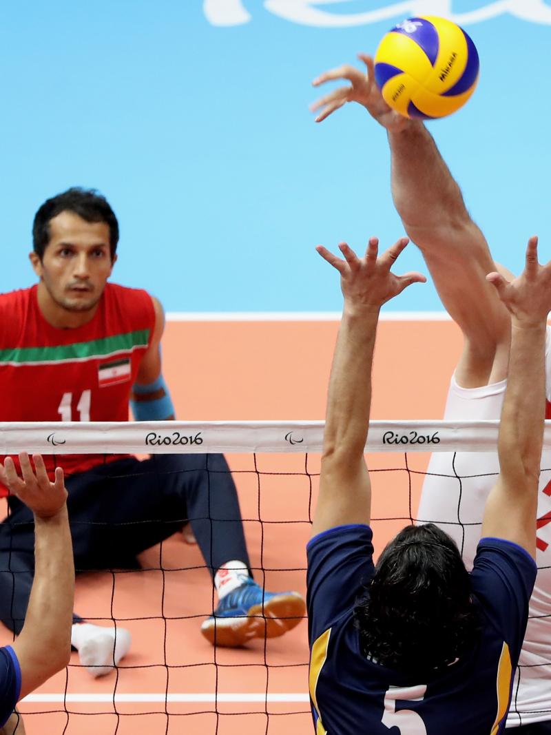 a male sitting volleyball player attempts a block
