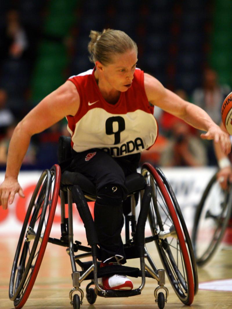 a female wheelchair basketballer dribbles the ball
