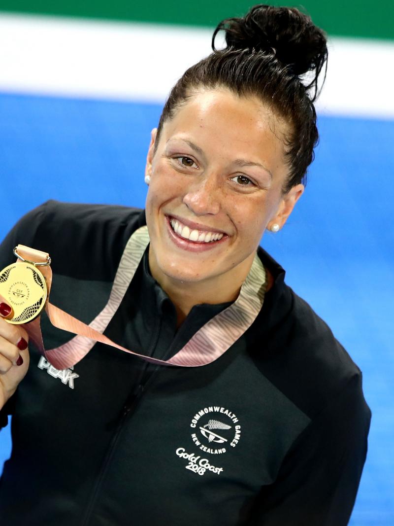 female Para swimmer Sophie Pascoe holds up a gold medal by the pool