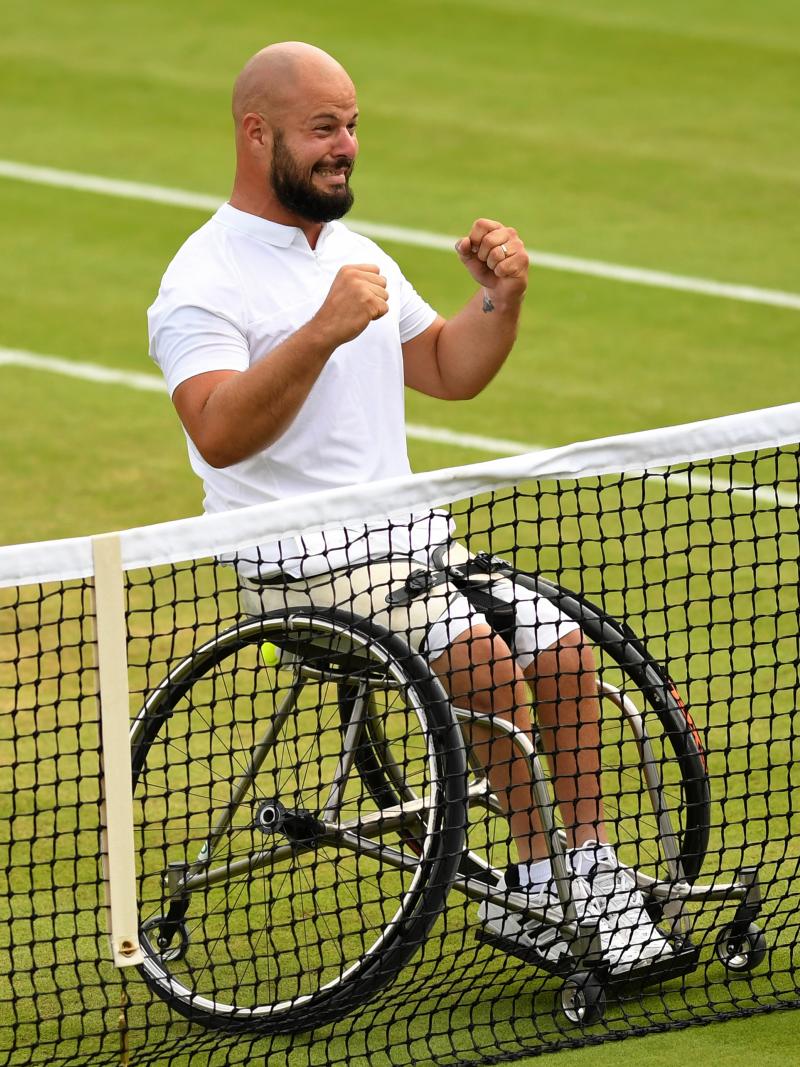 male wheelchair tennis player Stefan Olsson raises his fists in celebration at the net