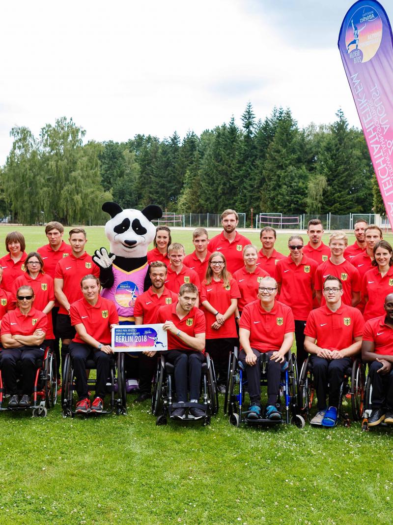 Group athletes standing and in wheelchairs meet Max the Para panda mascot