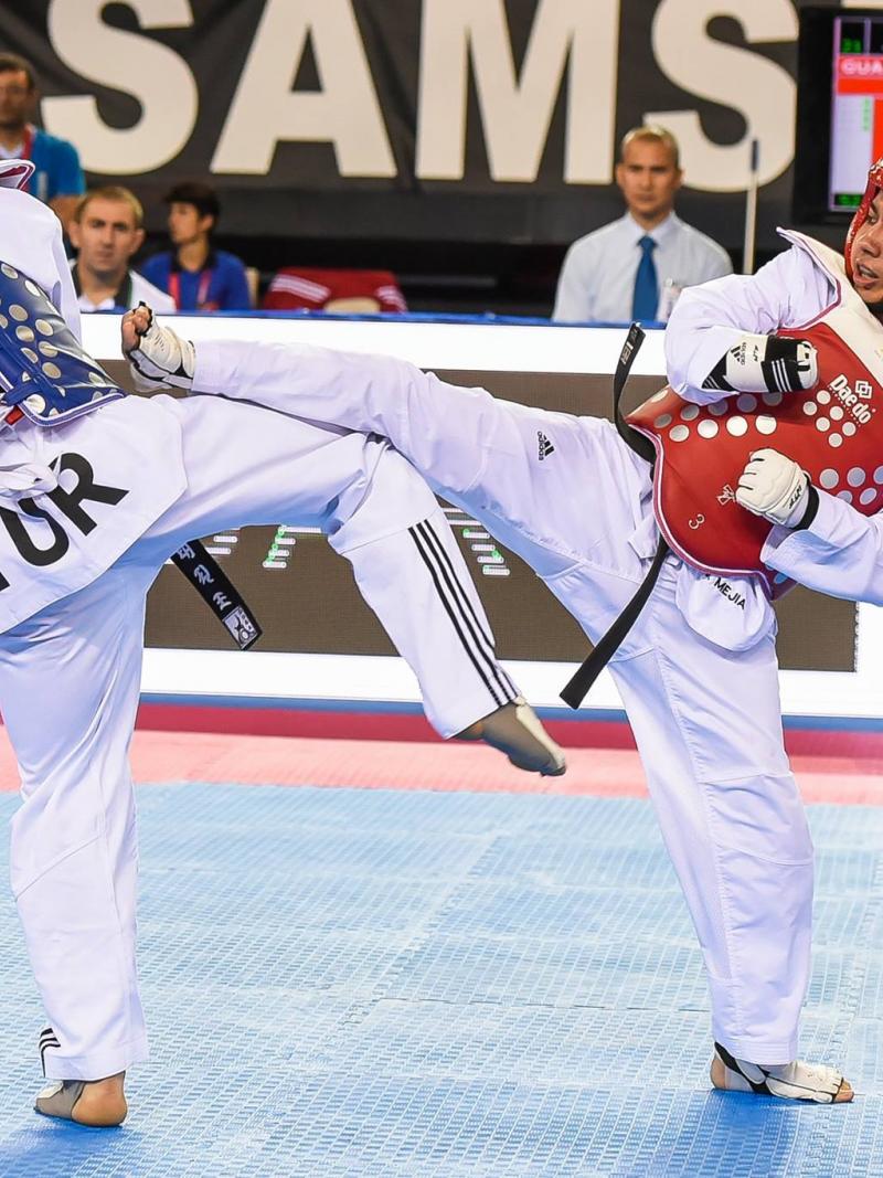 Two male taekwondo fighters kick each other