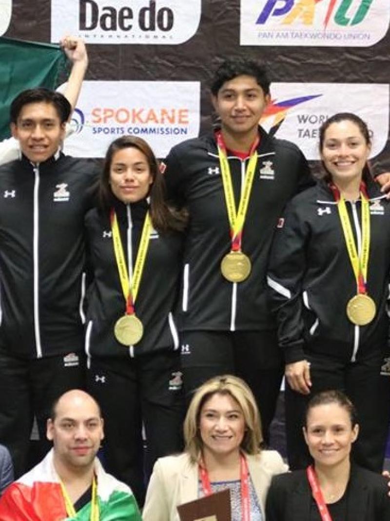 a group of male and female Para taekwondo fighters standing together with gold medals round their necks