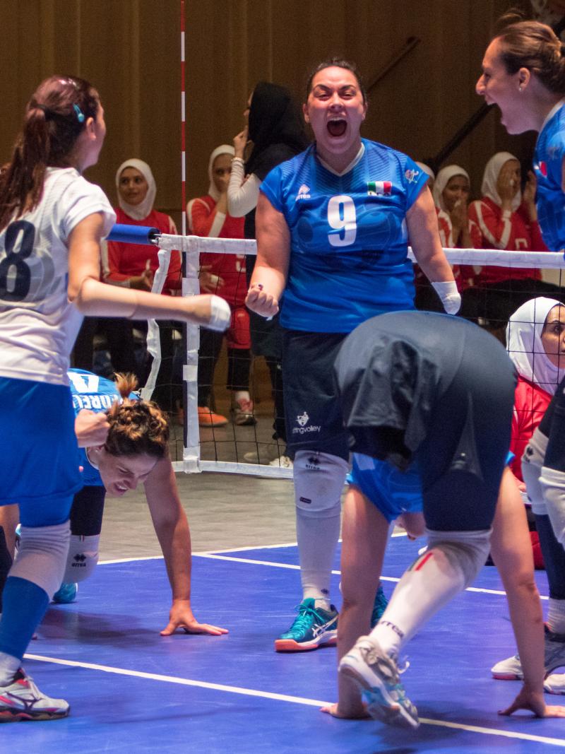 three female Italian sitting volleyball players celebrate on the court