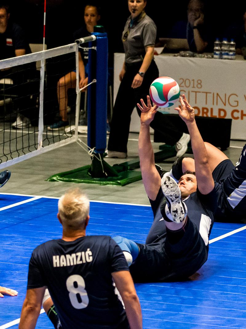 a group of Bosnian male sitting volleyball players working to get the ball back over the net