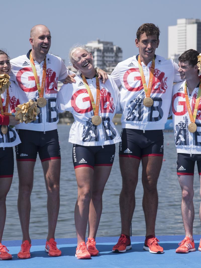 a group of five British Para rowers standing on the podium with their gold medals