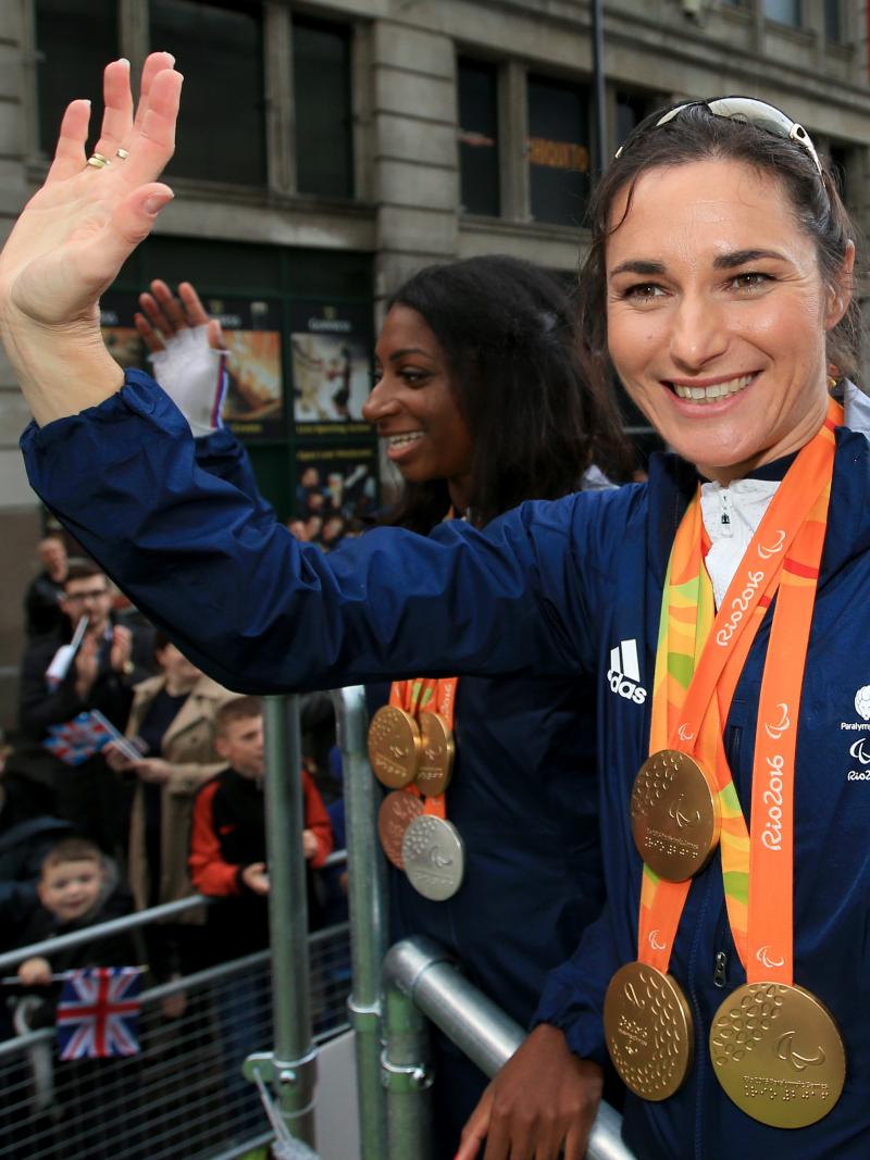 female Para cyclist Sarah Storey waves to fans from the top of a bus 