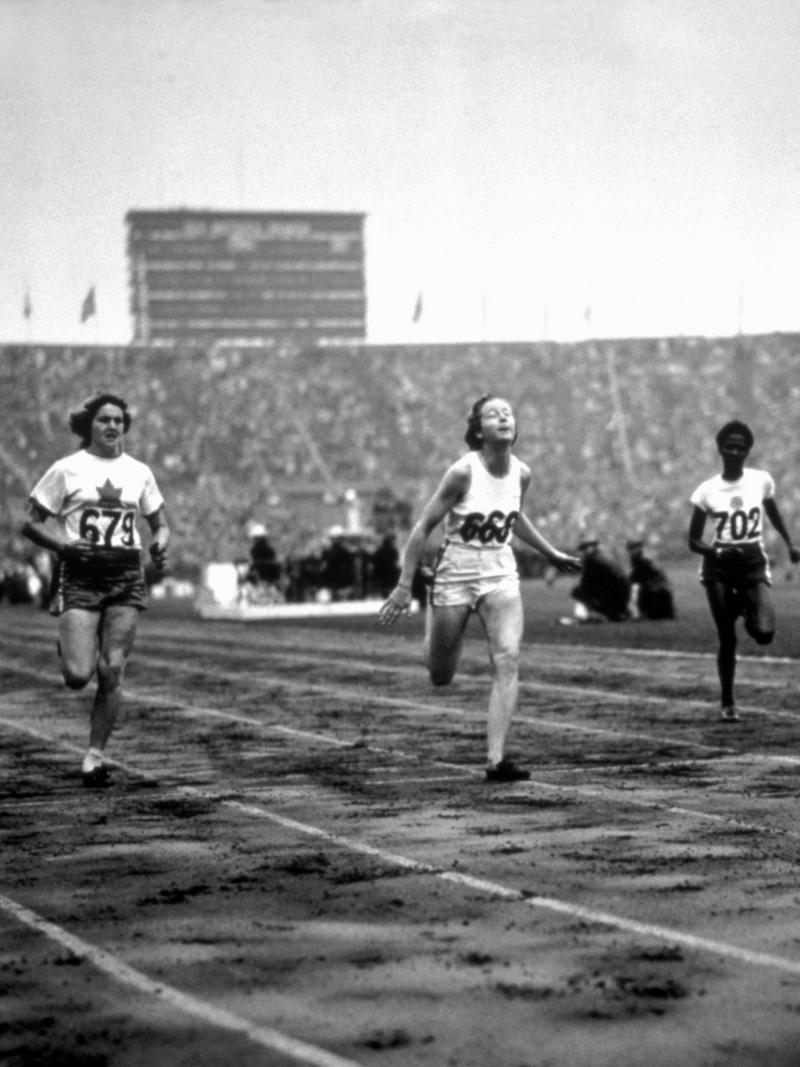 female sprinter Fanny Blankers-Koen crosses the finish line ahead of other female runners