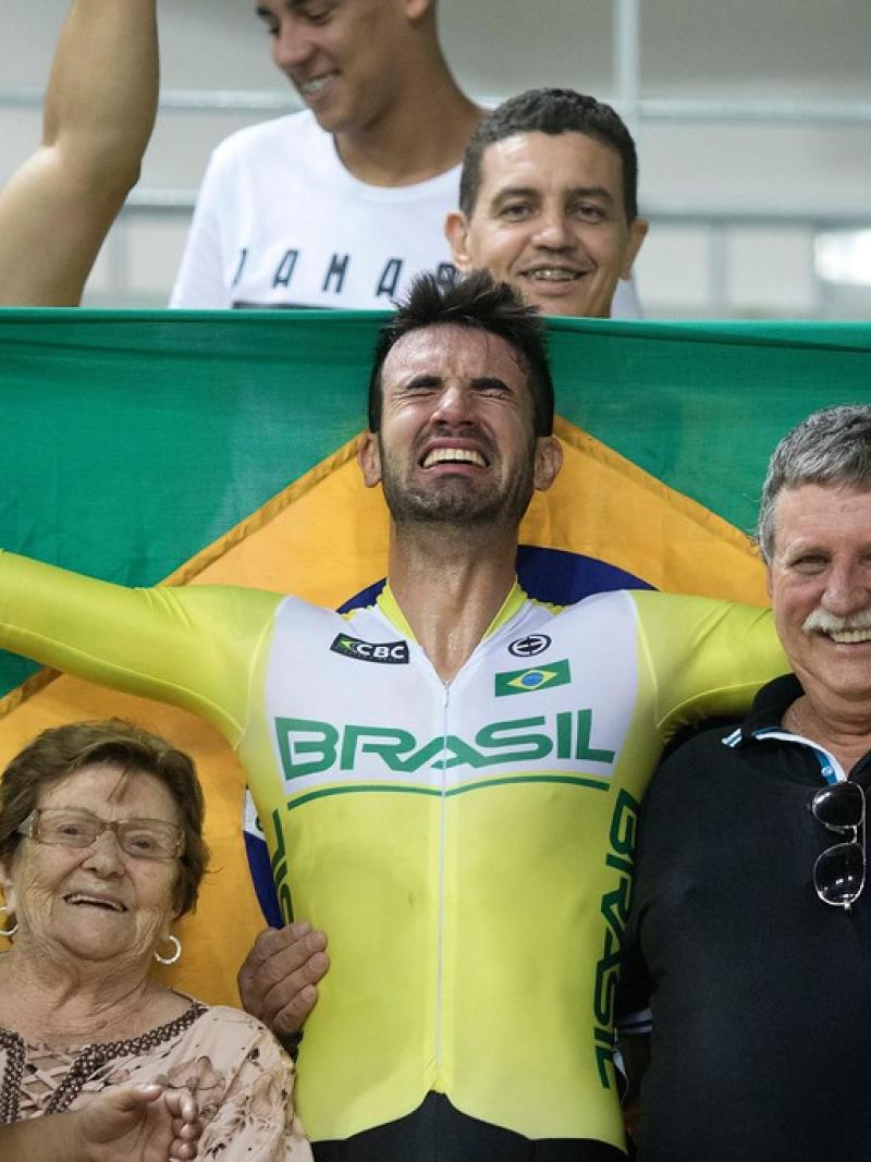 male Para cyclist Lauro Chaman celebrates with his family and holds up the Brazil flag