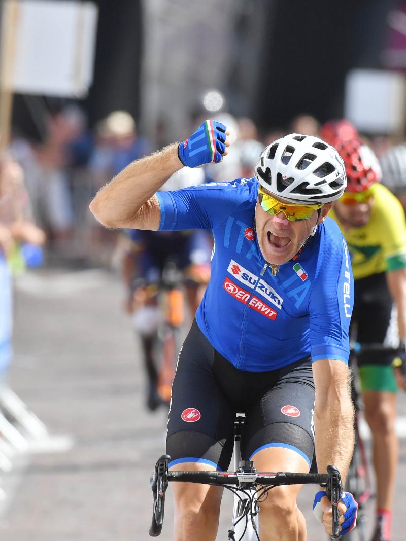 male Para cyclist Michele Pittacolo punches the air as he crosses the finish line