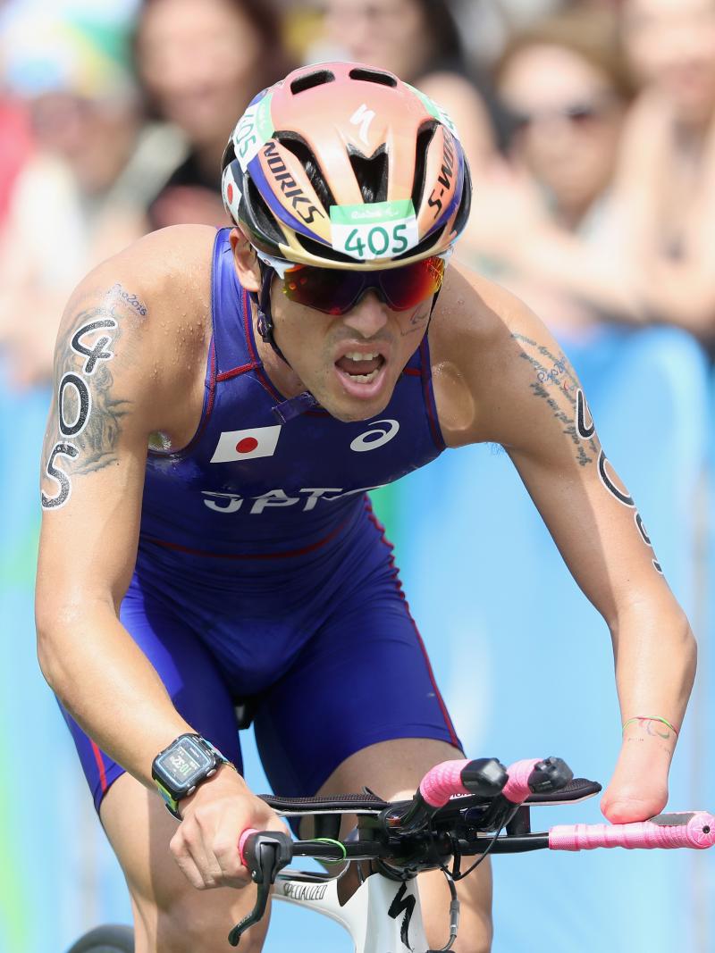 male Para triathlete Keiichi Sato racing on a bike