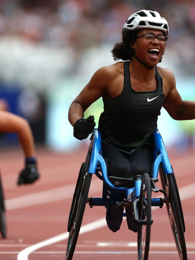 female wheelchair racer Kare Adenegan celebrates as she crosses the finish line