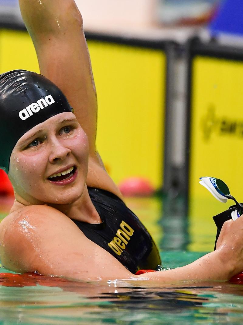 female Para swimmer Liesette Bruinsma raises her arm in celebration after winning her race