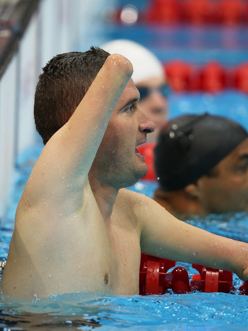 male Para swimmer Zsolt Vereczkei raises his arm in the water