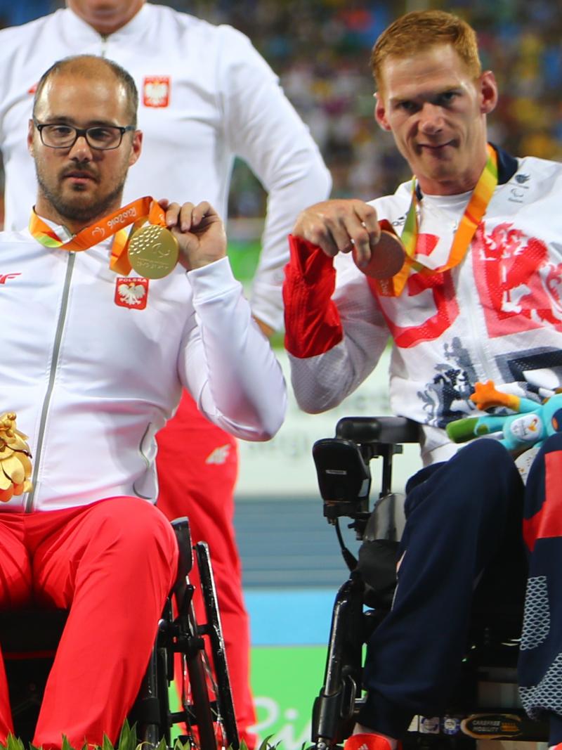 male Para athletes Stephen Miller and Maciej Sochal on the podium holding up their medals