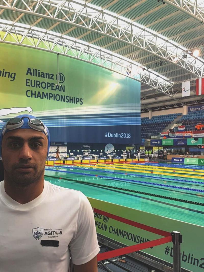 Man with swimming cap in front of a swimming pool