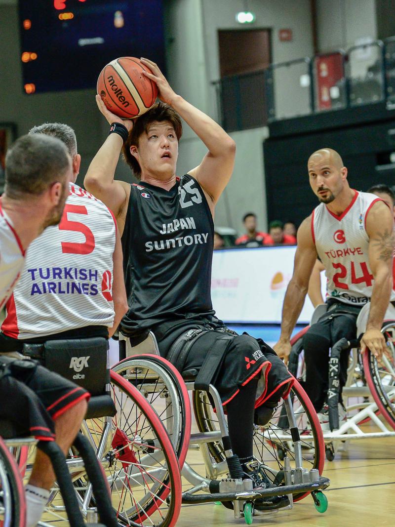 Man in wheelchair with a ball in his hands surrounded by other three men