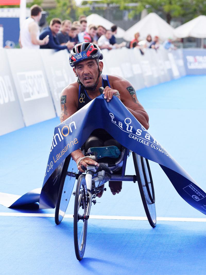 male Para triathlete Ahmed Andaloussi breaks the tape as he crosses the finish line