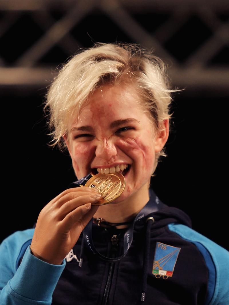 female wheelchair fencer Beatrice Vio bites a gold medal and smiles