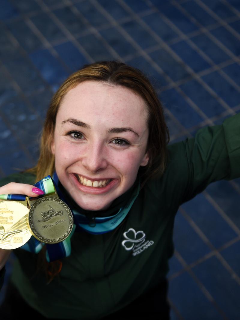 female Para swimmer Ellen Keane smiles and holds up her gold medal