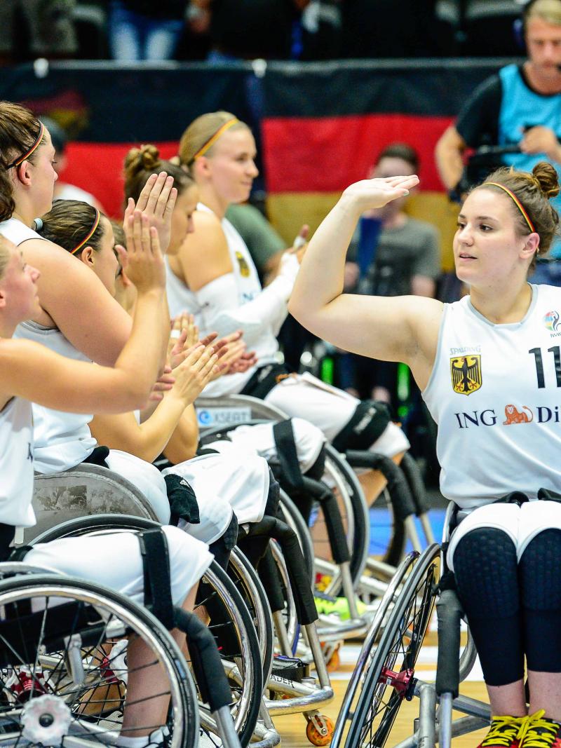 A female German wheelchair basketballer high fives her teammates
