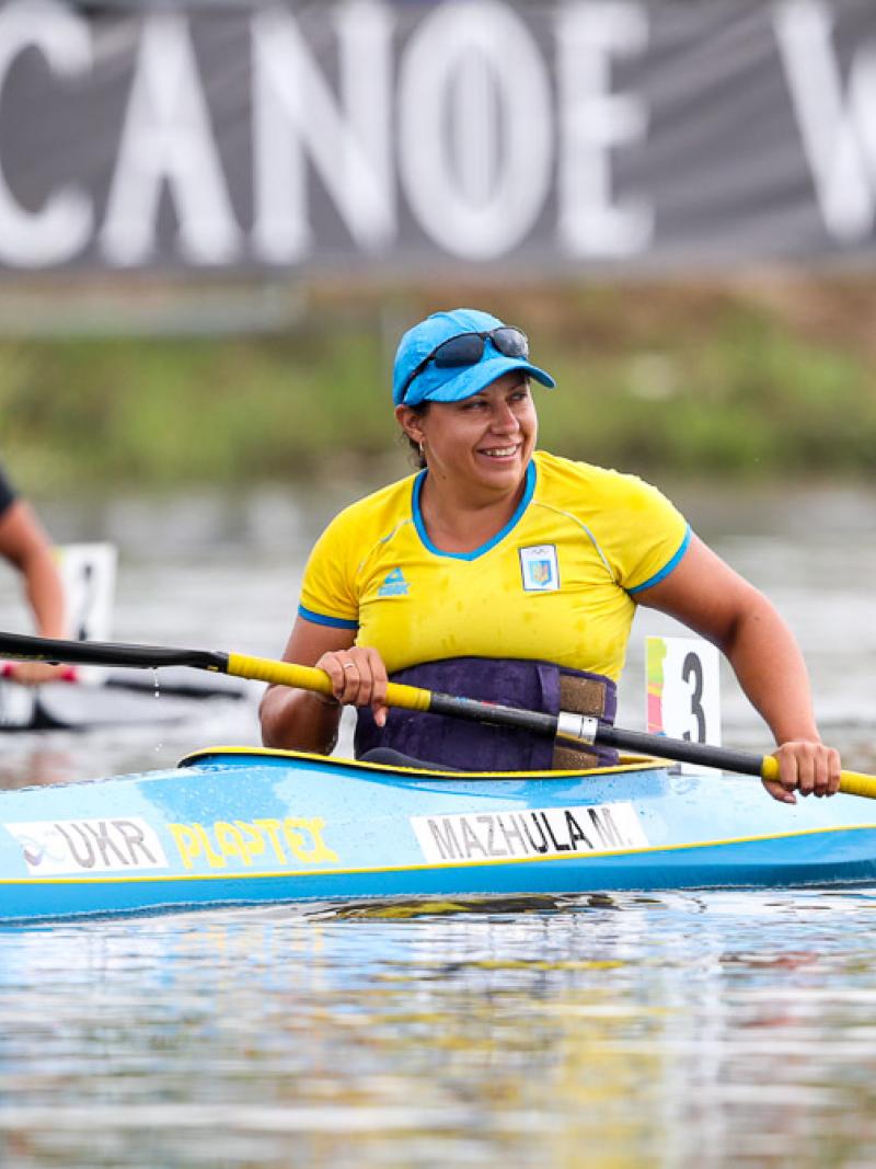 female Para canoeist Maryna Mazhula smiles in her boat after winning the race