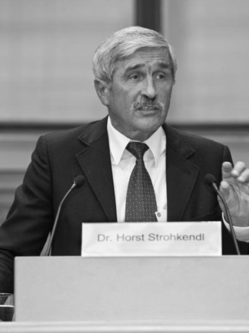 Black and white photo of a man in suit speaking at a podium
