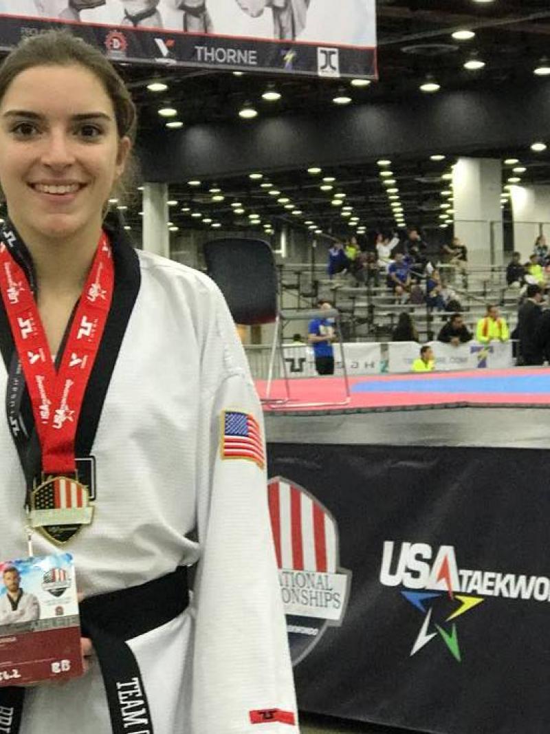 US woman taekwondo fighter poses with medal around her neck
