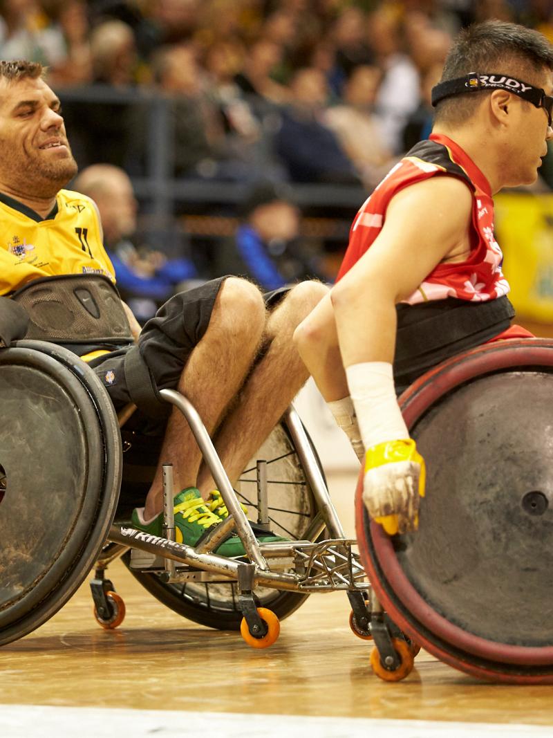 male wheelchair rugby player Ryan Scott chases another player with the ball