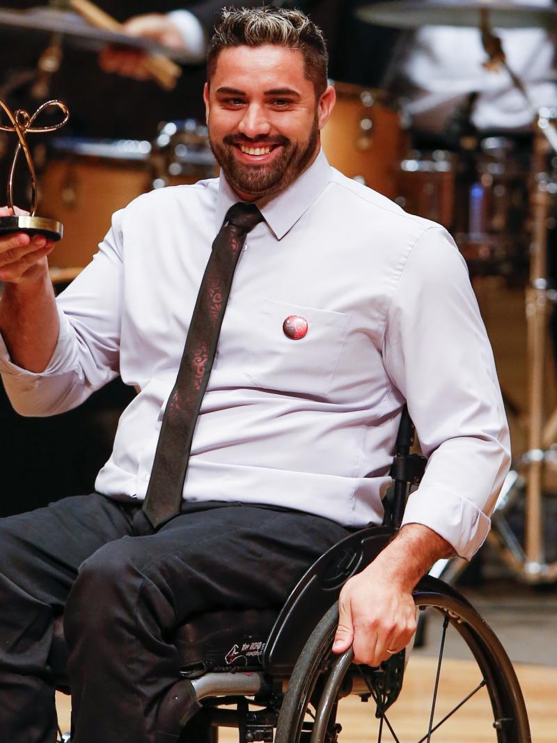 male wheelchair fencer Jovane Guissone holds up a trophy