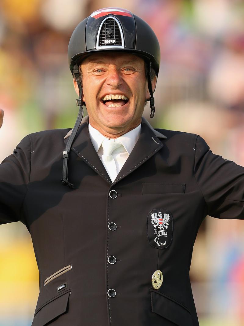 male Para equestrian rider Pepe Puch smiles and raises his hands in celebration