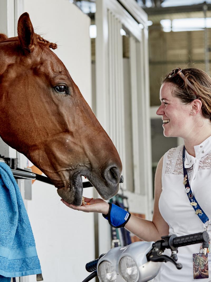 female Para equestrian rider Sanne Voets feeding her horse