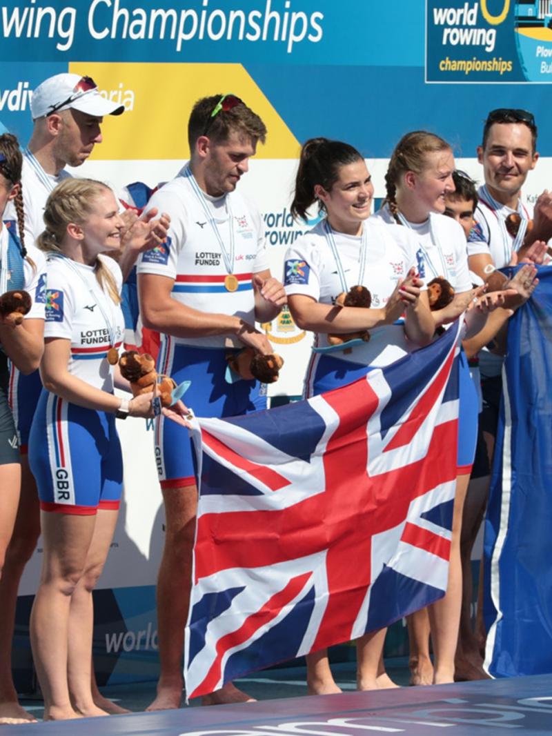 Group of female and male rowers on the podium with USA, Great Britain and France flags