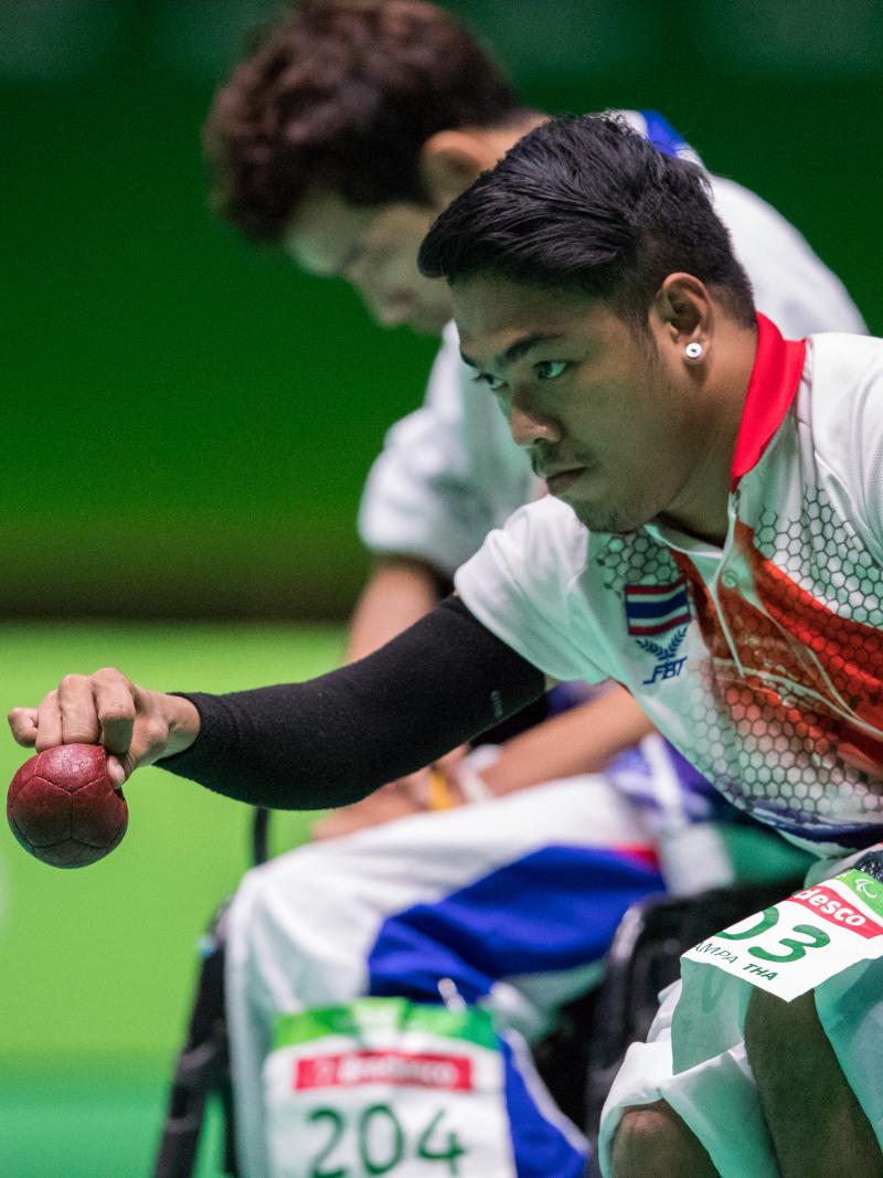 Man in a wheelchair throwing a red boccia ball