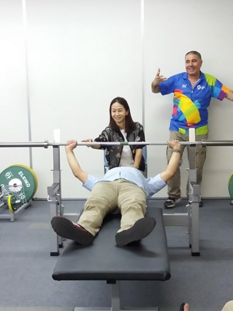 an official tries out the weight of a powerlifting bar while lying on the bench