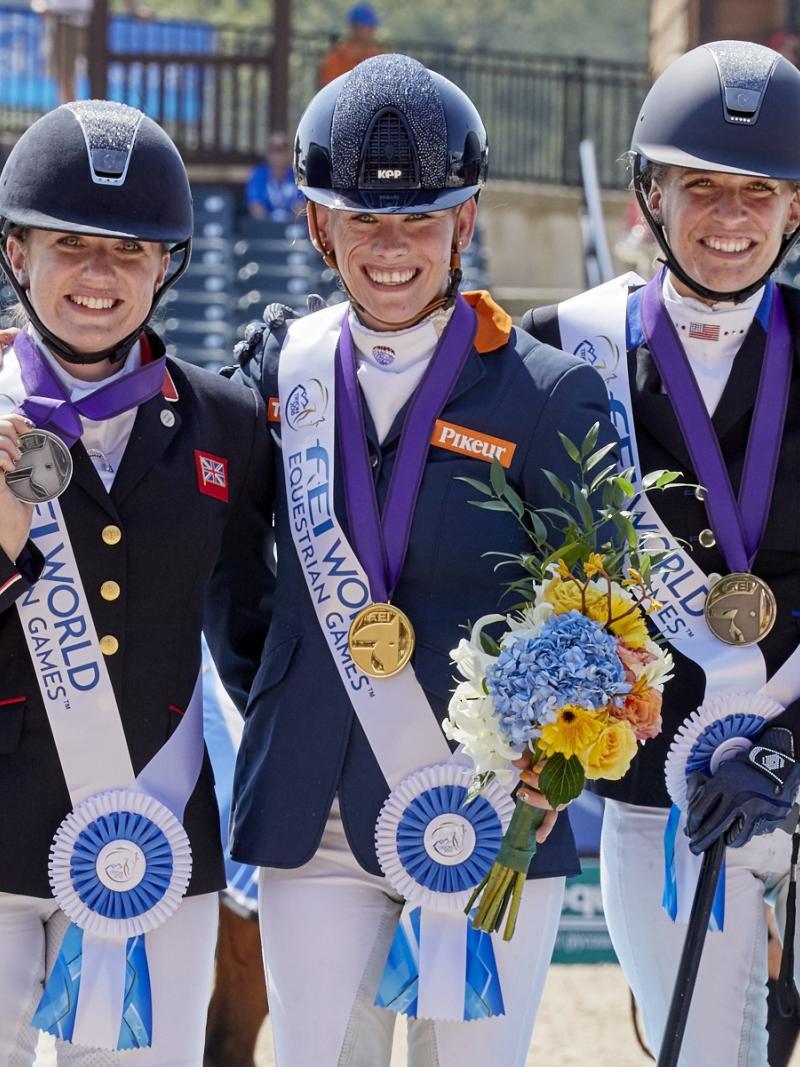 three female Para equestrian riders with Rixt van der Horst in the centre, standing on the podium
