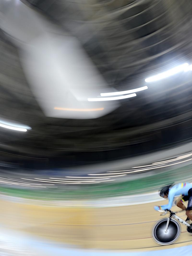 Man on track cycle rides around a velodrome
