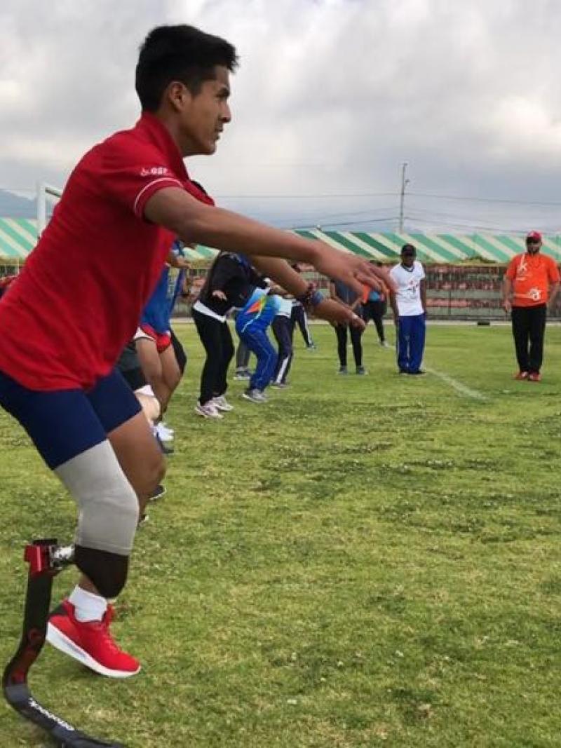 Man with prostethic leg standing on a football pitch