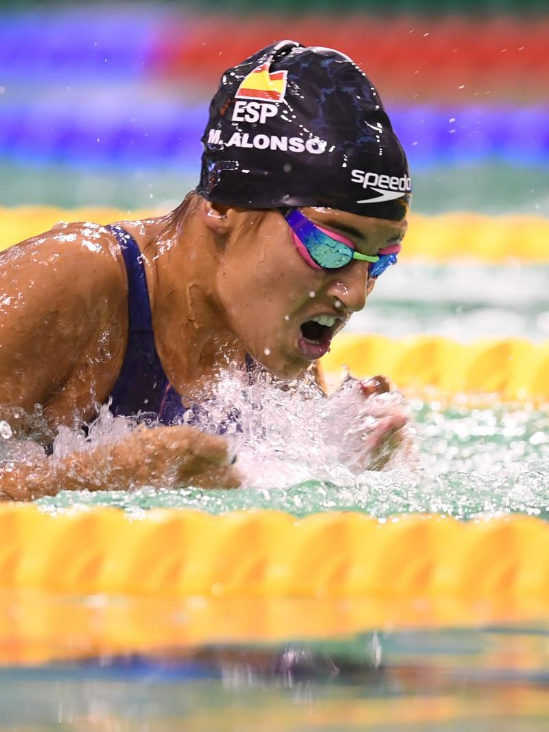 Woman swimming in the pool wearing a black cap with the Spanish flag