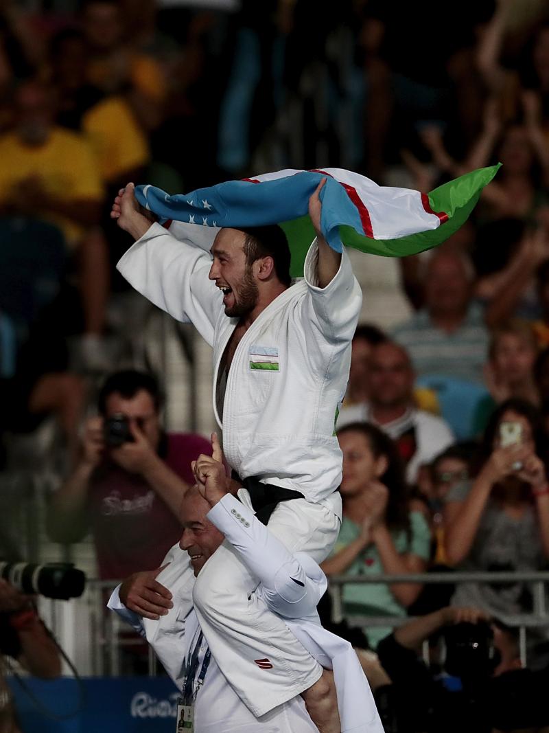 A man carrying Uzbekistan's flag on another man's shoulder
