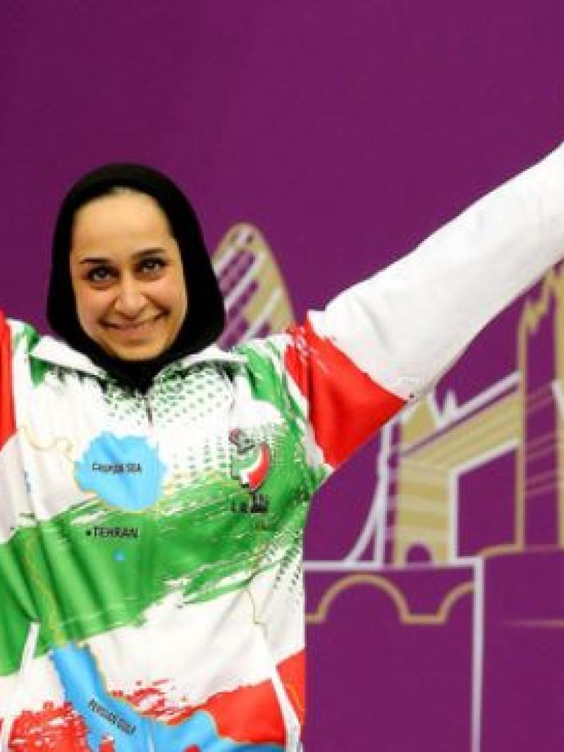 female Para shooter Sareh Javanmardi raises her arms on the podium