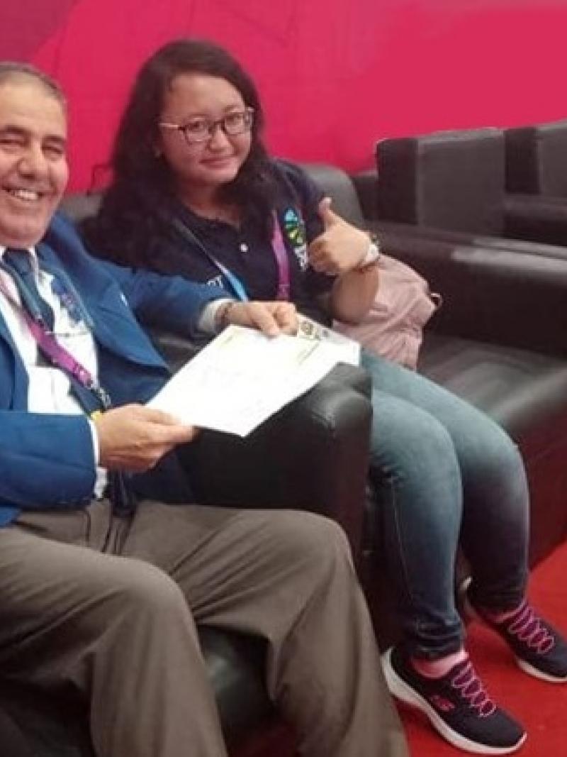 female powerlifting official Meytha Sarasvati gives a thumbs up to the camera