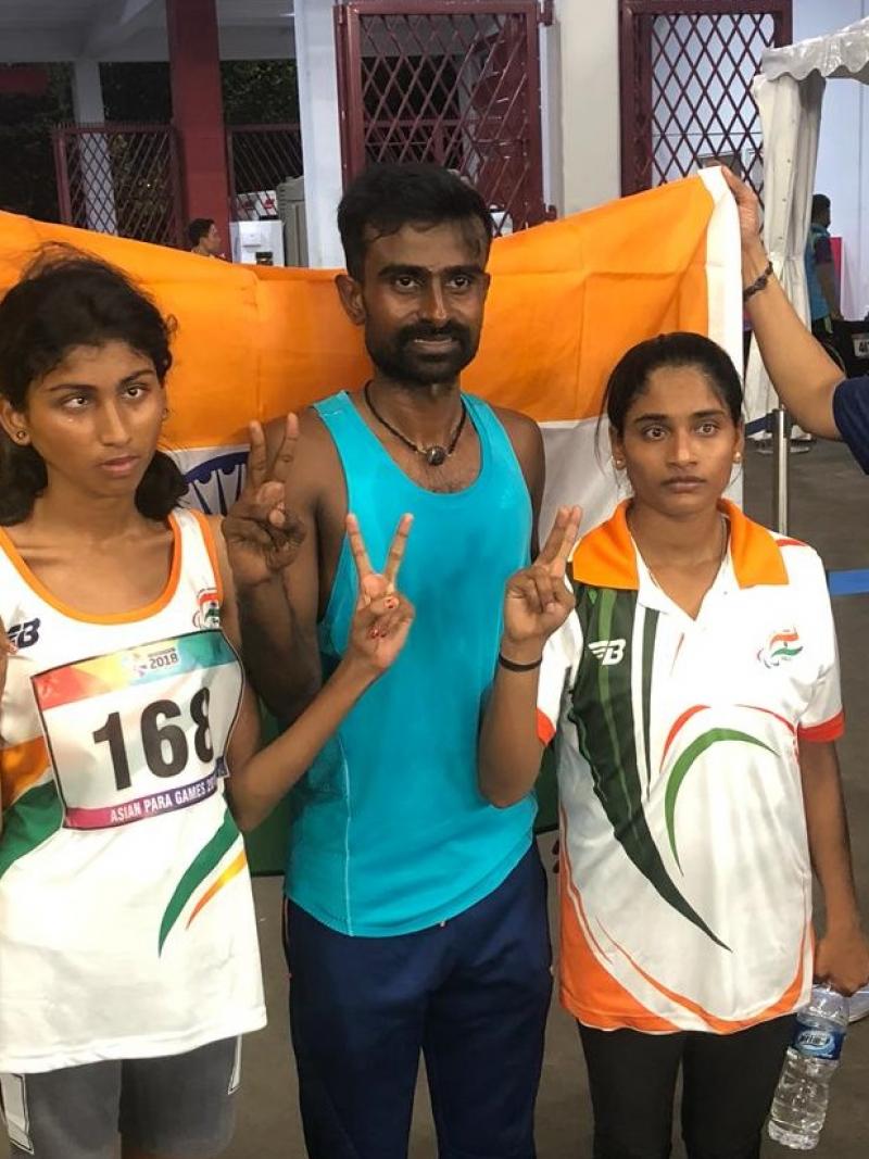 female Para athlete Rakshitha Raju standing with her guide in front of an India flag