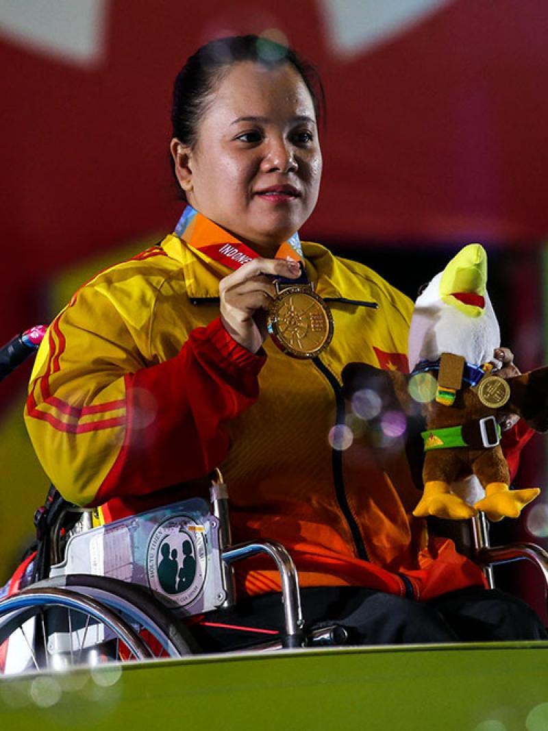 female powerlifter Dang Thi Linh Phuong on the podium holding up her gold medal